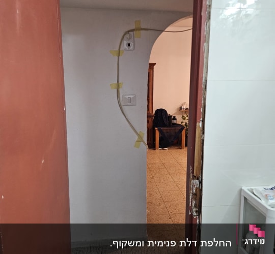 דלת פתוחה עם חוט חשמל מודבק לקיר